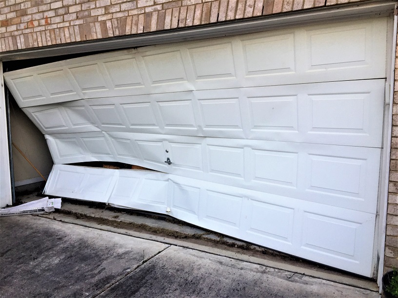 Broken garage door being inspected during an emergency repair in Orange County